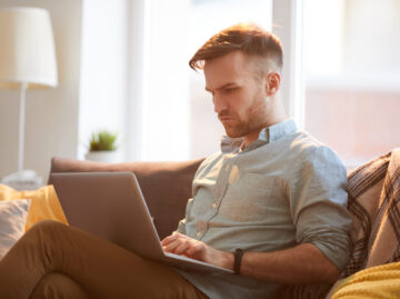Handsome Man Using Laptop at Home Versicherungsmakler Essen